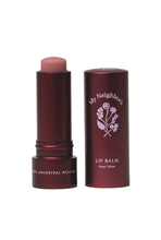 Load image into Gallery viewer, A rose-toned lip balm stick shown next to its metallic dark red tube packaging on a light gray background. The brand 'My Neighbor's' is visible on the tube.